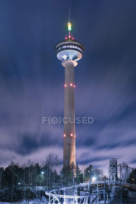 Torre de comunicações iluminada à noite no céu nublado — Fotografia de Stock