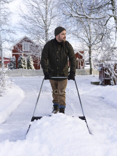 Man cleaning yard with snow pusher — Stock Photo