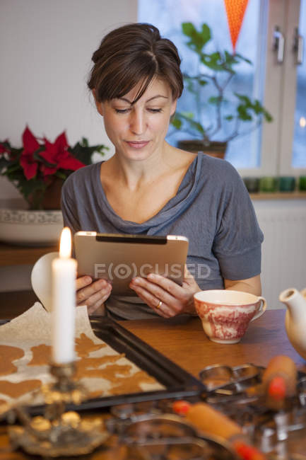 Woman using digital tablet at home table — Stock Photo