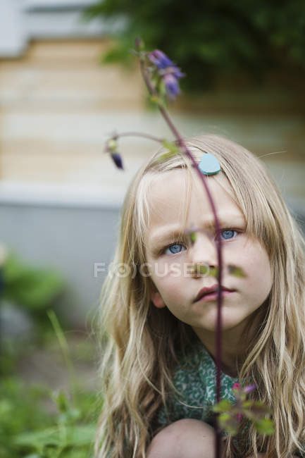 Девушка смотрит на цветок, избирательный фокус — стоковое фото