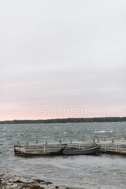 Wooden pier with moored boat at dusk — Stock Photo