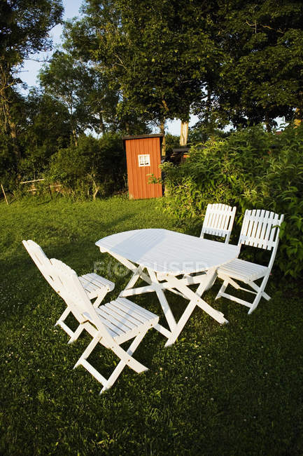 Mesa branca e cadeiras no jardim iluminado sol — Fotografia de Stock