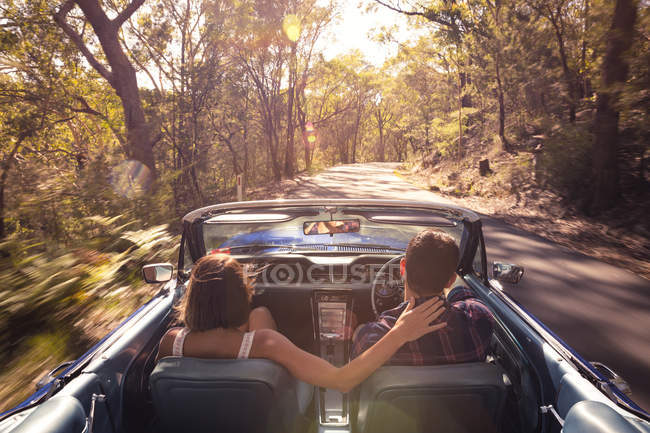 Couple driving car through forest — Stock Photo