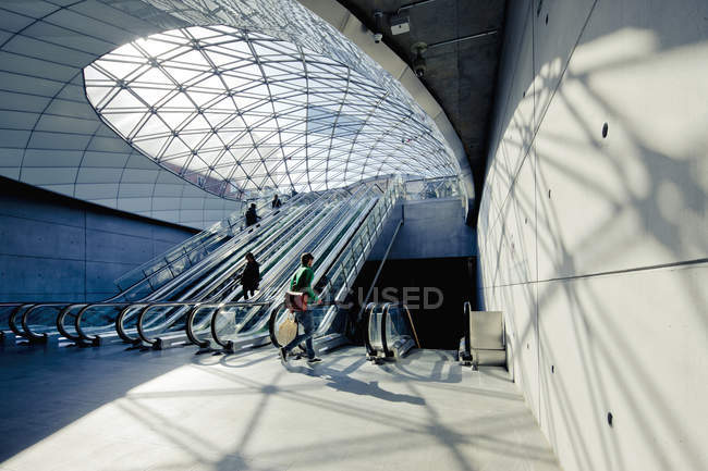 Personnes sur les escaliers roulants éclairés par le soleil dans le tunnel — Photo de stock