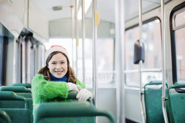 Young woman sitting in tram, leaning on grab rail — Stock Photo