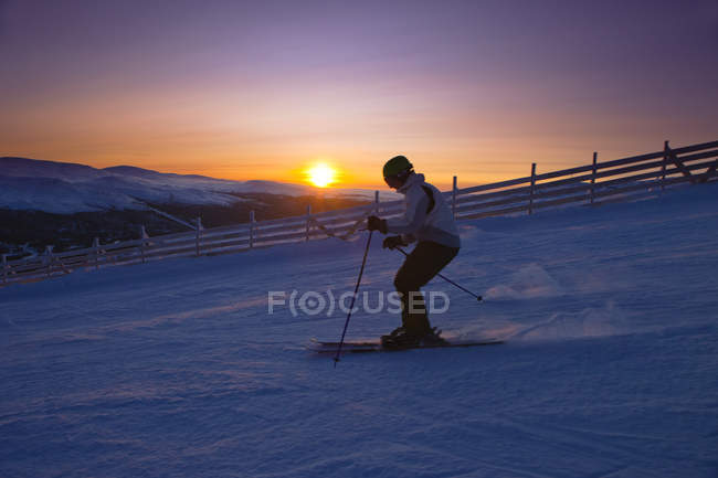 Vista lateral do homem esquiando ao pôr do sol — Fotografia de Stock