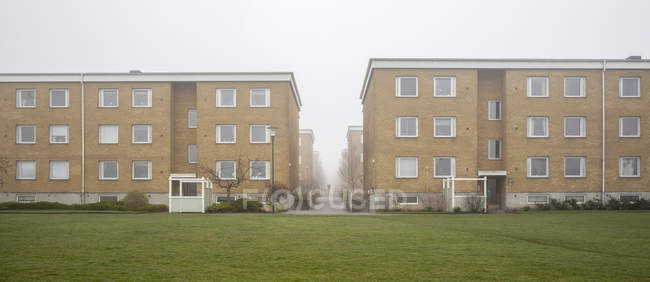 Edifici residenziali e prato verde nella nebbia — Foto stock
