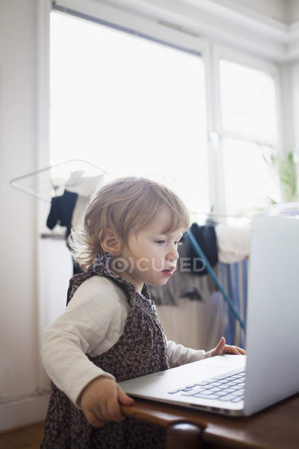 Chica mirando a la computadora portátil, enfoque diferencial - foto de stock