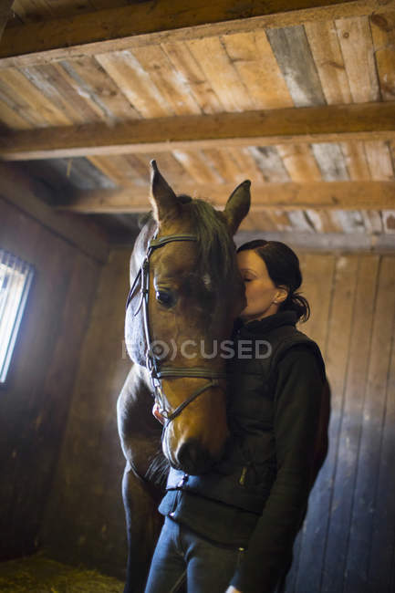 Donna che sussurra al cavallo nelle scuderie, attenzione selettiva — Foto stock