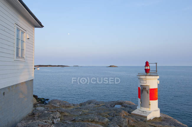 Маленький маяк на берегу моря с закатом неба — стоковое фото