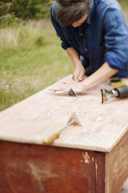 Mujer puliendo madera, enfoque diferencial - foto de stock