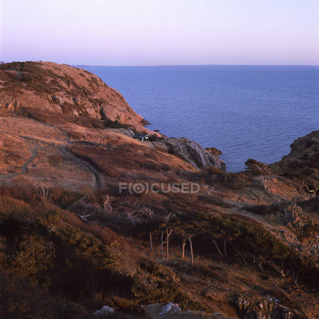 Imagem de uma casa distante sobre rochas ao pôr-do-sol — Fotografia de Stock