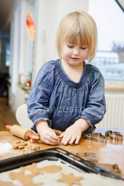 Chica con cabello rubio haciendo galletas - foto de stock