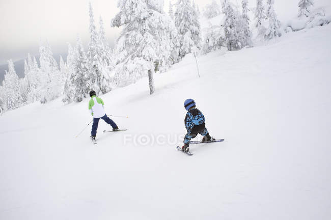 Чоловік і хлопчик катаються на лижах вниз по схилу, вибірковий фокус — стокове фото