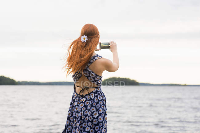 Вид сзади молодой женщины, фотографирующей море — стоковое фото