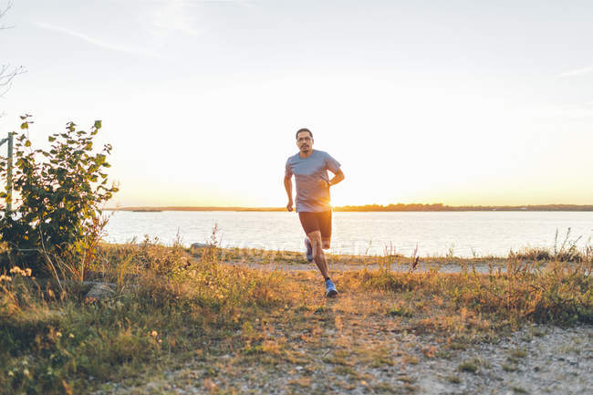 Homme adulte mi-jogging au bord de la mer — Photo de stock