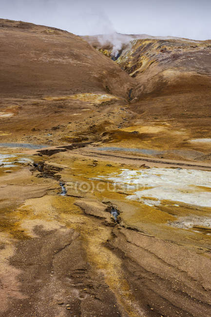 Vapor sobre aguas termales entre montañas rocosas en Islandia - foto de stock