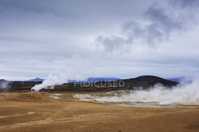 Vapore sopra sorgenti termali con catena montuosa all'orizzonte — Foto stock