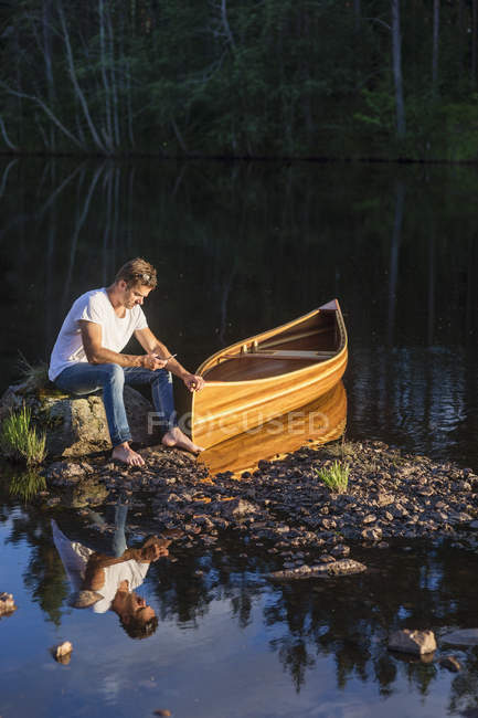 Man sitting on boulder in middle of lake — Stock Photo