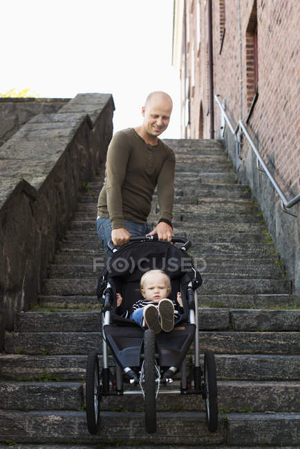 Pai empurrando carrinho com bebê filho, diminuindo a perspectiva — Fotografia de Stock