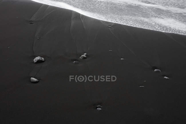Areia preta e rochas na superfície da praia, Islândia — Fotografia de Stock