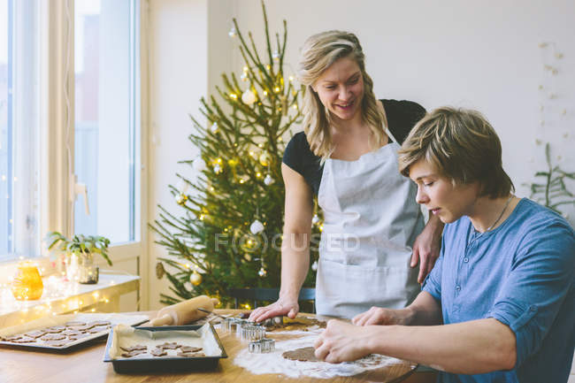 Casal preparando biscoitos de Natal na sala de jantar — Fotografia de Stock