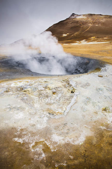 Пар над горячими источниками с горным хребтом в Исландии — стоковое фото