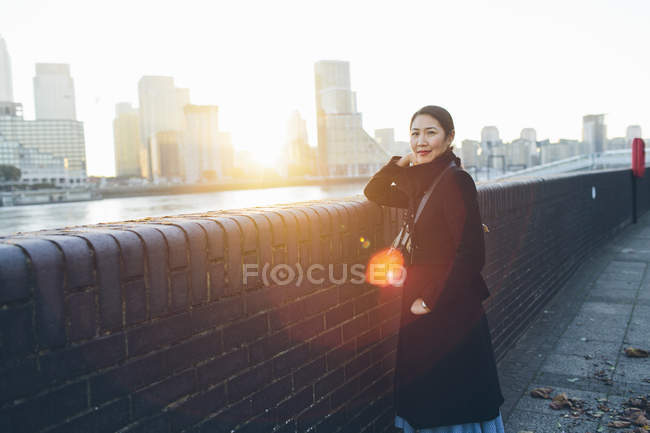 Mid adult woman leaning against wall on riverbank in Rotherhithe — Stock Photo