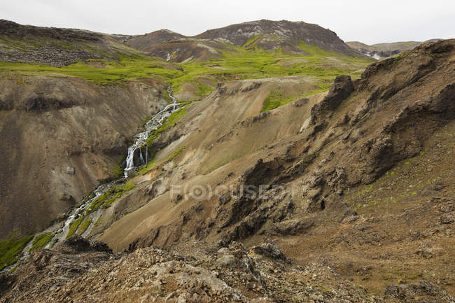 Cascata che scorre nella verde valle rocciosa, Islanda — Foto stock