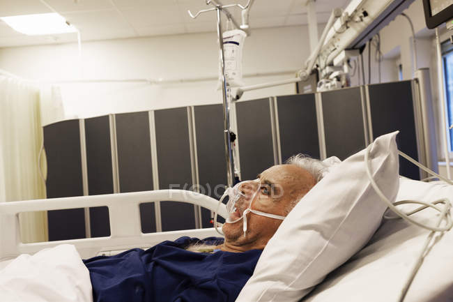 Senior man lying down on hospital bed — Stock Photo