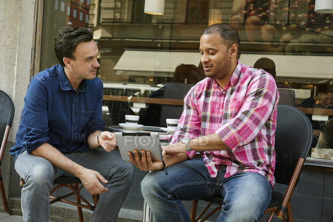Hommes matures utilisant une tablette numérique dans un café de trottoir — Photo de stock