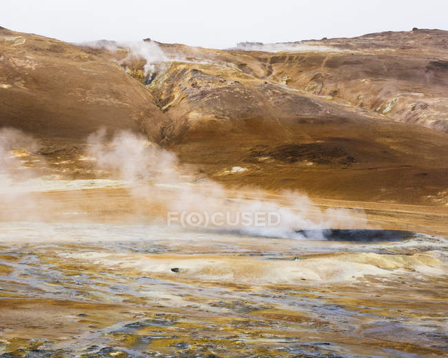 Vapore sulle sorgenti termali con catena montuosa in Islanda — Foto stock
