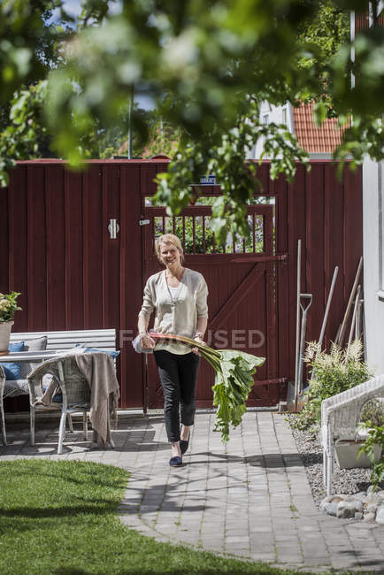 Mulher madura carregando acelga no quintal — Fotografia de Stock