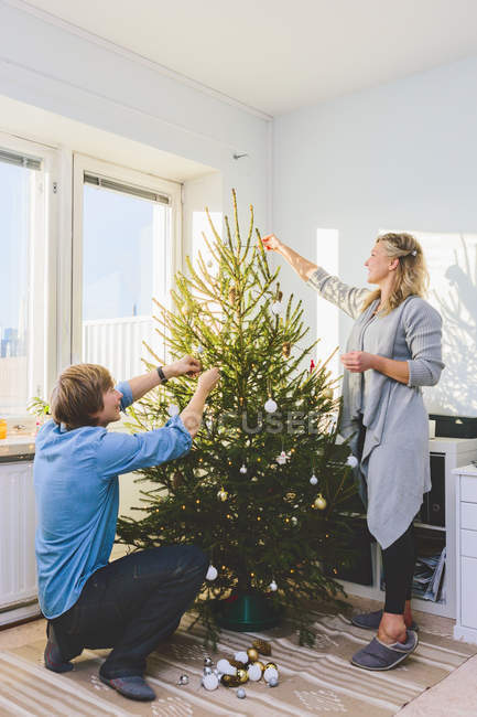 Side view of couple decorating christmas tree together — Stock Photo