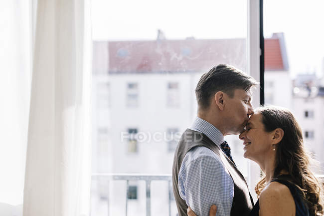 Couple hugging by window, focus on foreground — Stock Photo