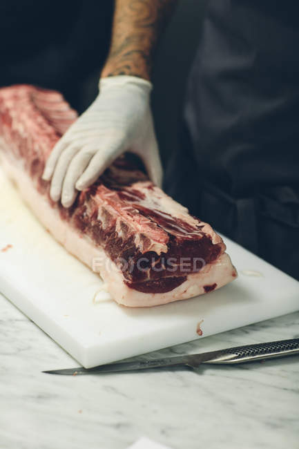 Butcher hand in protective glove preparing meat — Stock Photo