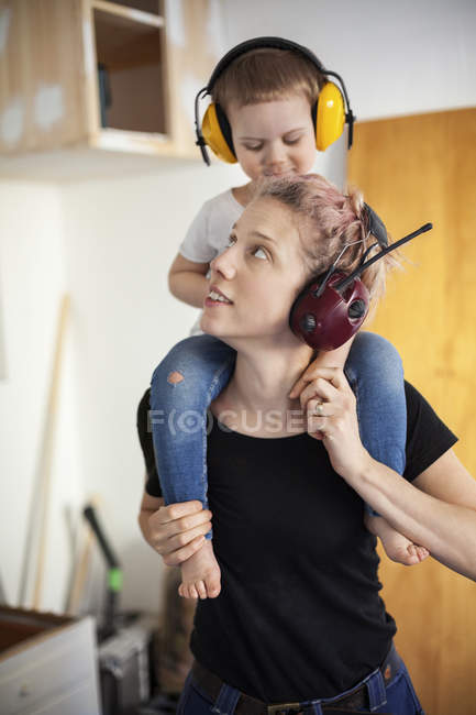 Средняя взрослая женщина плотник, несущая сына на плечах — стоковое фото