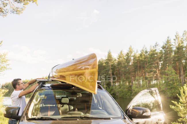 Uomo in piedi in auto con kayak sul tetto — Foto stock