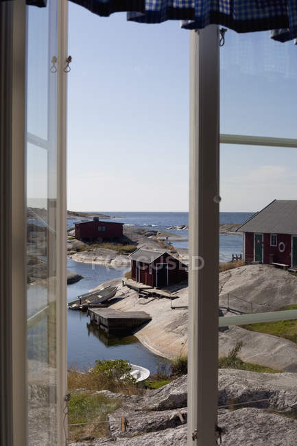 Holzhäuser am felsigen Meeresufer aus dem Fenster gesehen — Stockfoto