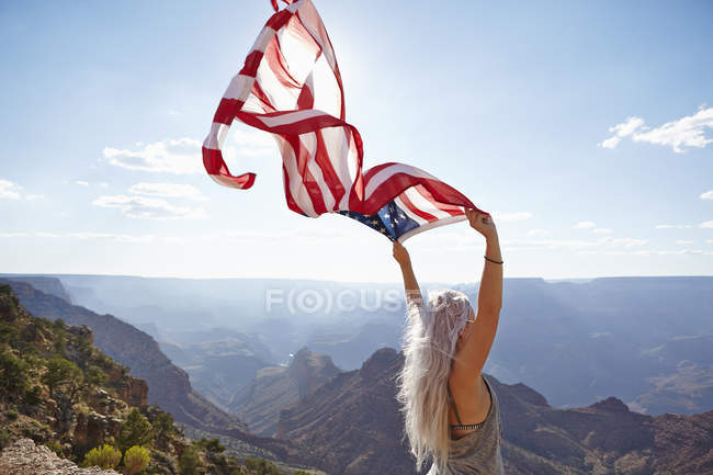 Jeune femme tenant le drapeau américain au Grand Canyon — Photo de stock