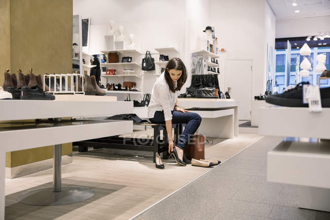 Young adult woman trying on shoes in store — Stock Photo