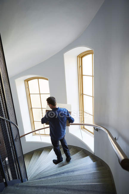 Hochwinkel-Ansicht des Mannes, der auf Stufen geht, trägt Box — Stockfoto