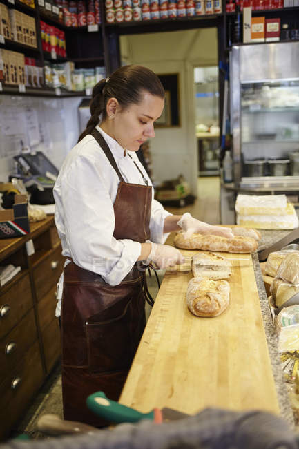 Vista lateral da mulher cortando pão na loja — Fotografia de Stock