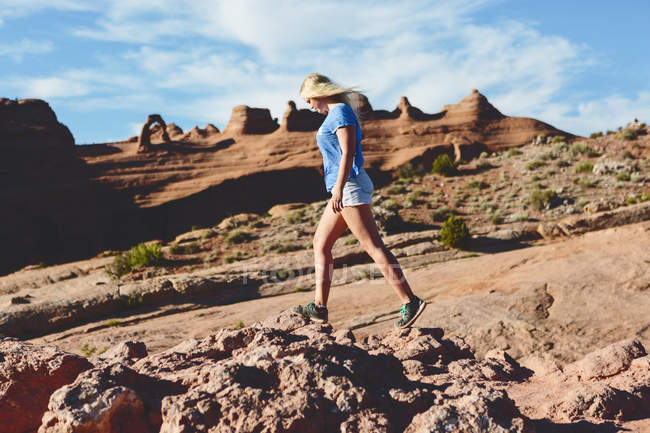 Vista laterale della donna che cammina sulle rocce nel Parco Nazionale degli Archi — Foto stock