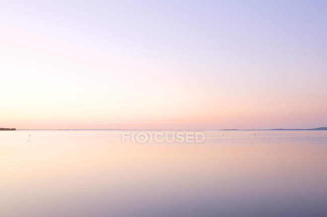 Vista panorámica del cielo rosado atardecer reflejándose en el agua del lago - foto de stock