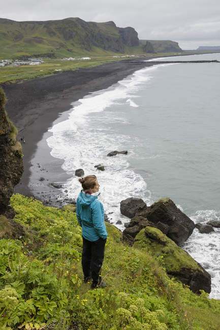 Hiker looking from cliff at black sand beach in Iceland — Stock Photo
