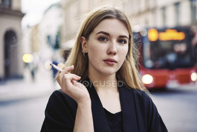 Retrato de una joven fumando en la calle - foto de stock