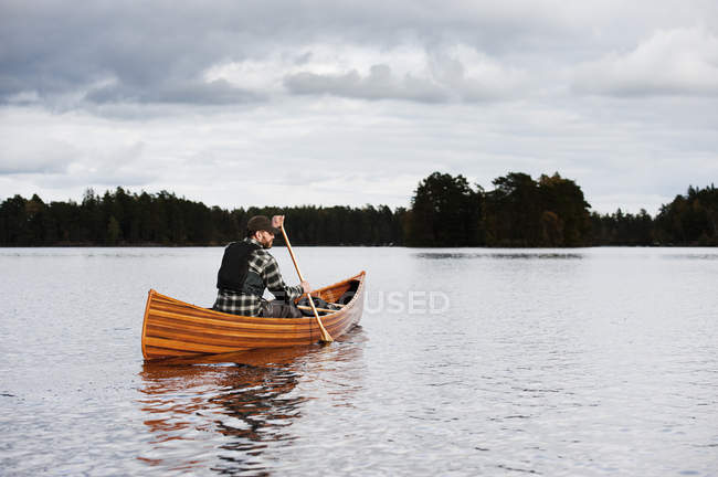 Man paddling canoe on lake at autumn — Stock Photo