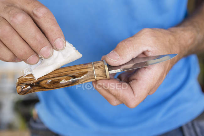 Homem lubrificando faca de madeira, foco em primeiro plano — Fotografia de Stock
