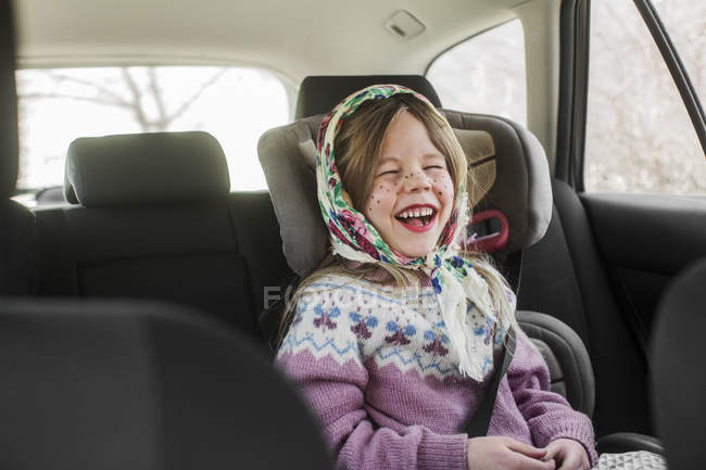Girl dressed up as Easter witch wearing headscarf laughing in car — Stock Photo